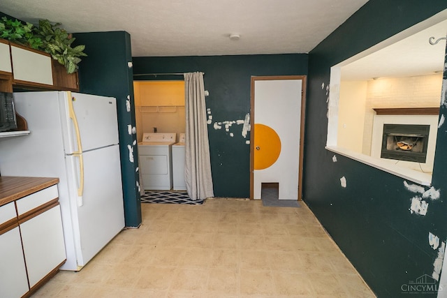 881 Trails End Dr, Liberty Twp, OH 45050 - kitchen with freestanding refrigerator, independent washer and dryer, white cabinetry, a fireplace, and light flooring
