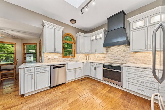 3067 Sugartree Rd, Tate Twp, OH 45106 - kitchen featuring appliances with stainless steel finishes, custom range hood, a skylight, backsplash, and light stone counters