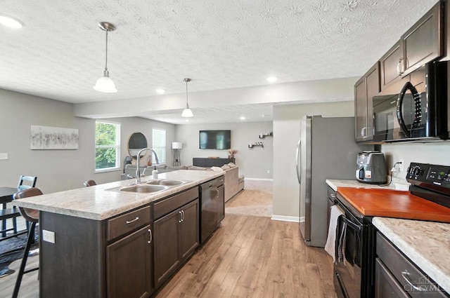 2821 Pine Leaf Ct, Hamilton, OH 45013 - kitchen featuring black appliances, light wood finished floors, dark brown cabinetry, an island with sink, and light countertops