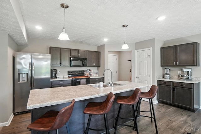 2821 Pine Leaf Ct, Hamilton, OH 45013 - kitchen with black appliances, a textured ceiling, dark wood-style floors, light countertops, and a kitchen bar