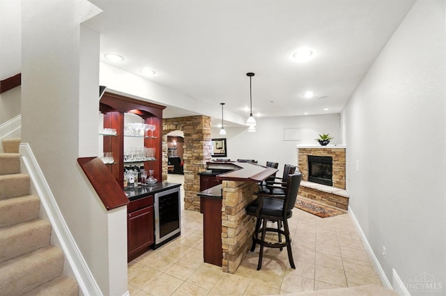 7070 Ravens Run, Anderson Twp, OH 45244 - indoor wet bar with wine cooler, stairway, a stone fireplace, light tile patterned flooring, and decorative light fixtures