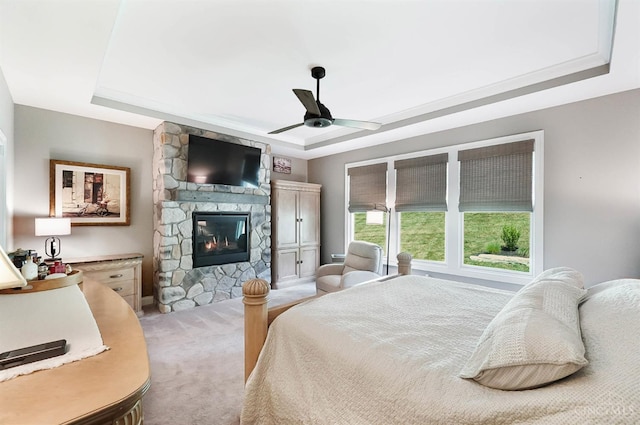 7574 Copper Creek Ln, Colerain Twp, OH 45247 - bedroom featuring a raised ceiling, light carpet, a stone fireplace, and a ceiling fan