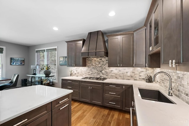 7574 Copper Creek Ln, Colerain Twp, OH 45247 - kitchen with custom range hood, stainless steel gas stovetop, dark brown cabinets, decorative backsplash, and recessed lighting