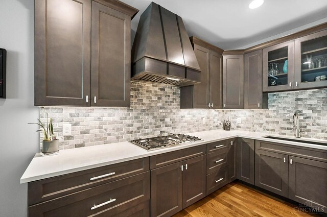 7574 Copper Creek Ln, Colerain Twp, OH 45247 - kitchen with custom exhaust hood, stainless steel gas cooktop, light countertops, and dark brown cabinetry