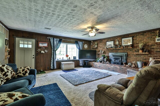 1851 Parker Rd, Goshen Twp, OH 45150 - living area with carpet floors, ceiling fan, a wood stove, wood walls, and a textured ceiling
