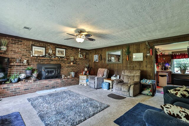 1851 Parker Rd, Goshen Twp, OH 45150 - living room featuring carpet flooring, a wood stove, a textured ceiling, a ceiling fan, and wood walls