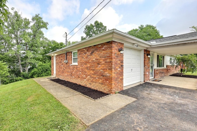 906 Shayler Rd, Union Twp, OH 45245 - view of side of home with a garage, brick siding, asphalt driveway, and a lawn