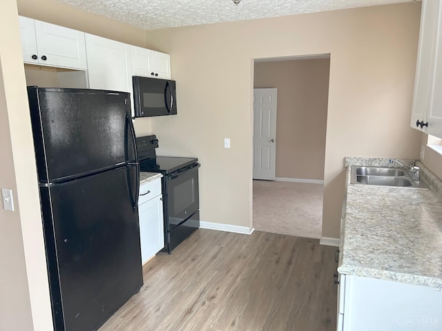 2247 Tucker Rd, Blanchester, OH 45107 - kitchen featuring black appliances, white cabinets, light wood-type flooring, light countertops, and a textured ceiling