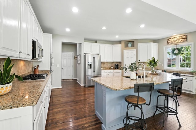 4048 Frye Park Cir, Mason, OH 45040 - kitchen featuring stainless steel appliances, dark wood-style floors, white cabinets, decorative backsplash, and a kitchen bar