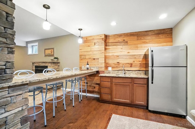 4048 Frye Park Cir, Mason, OH 45040 - kitchen featuring freestanding refrigerator, wooden walls, brown cabinetry, dark wood-type flooring, and hanging light fixtures