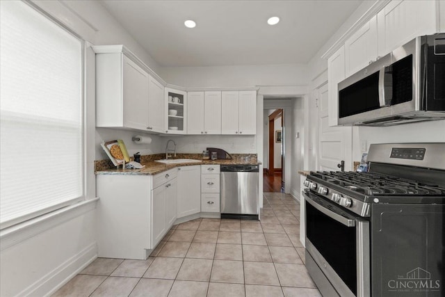 3131 Troy Ave, Cincinnati, OH 45213 - kitchen with stainless steel appliances, white cabinetry, glass insert cabinets, light tile patterned floors, and dark stone countertops
