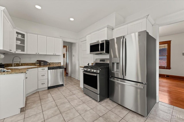 3131 Troy Ave, Cincinnati, OH 45213 - kitchen featuring appliances with stainless steel finishes, white cabinets, glass insert cabinets, light tile patterned floors, and stone countertops