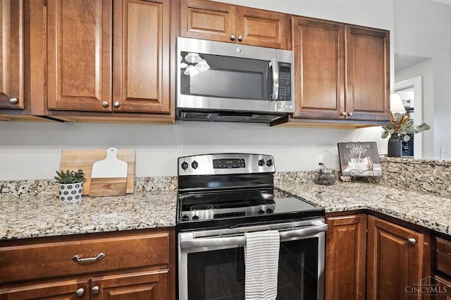 8135 Faller Rd, Hamilton Twp, OH 45039 - kitchen with appliances with stainless steel finishes, light stone counters, and brown cabinets