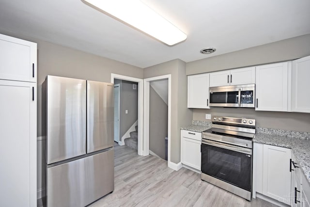 64 Craig Dr, Hamilton, OH 45013 - kitchen featuring appliances with stainless steel finishes, white cabinetry, light wood finished floors, and light stone countertops