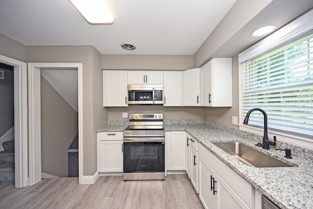 64 Craig Dr, Hamilton, OH 45013 - kitchen with stainless steel appliances, light wood finished floors, white cabinets, and light stone counters