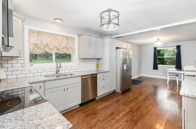 3340 Algus Ln, Green Twp, OH 45248 - kitchen with stainless steel appliances, decorative backsplash, dark wood-style flooring, light stone countertops, and hanging light fixtures