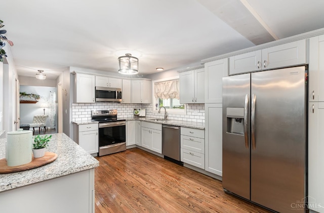 3340 Algus Ln, Green Twp, OH 45248 - kitchen featuring stainless steel appliances, backsplash, wood finished floors, light stone countertops, and white cabinets