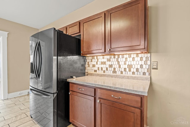 5824 Saranac Ave, Cincinnati, OH 45224 - kitchen with stainless steel fridge, tasteful backsplash, light countertops, and brown cabinets