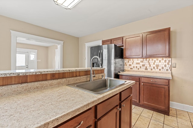 5824 Saranac Ave, Cincinnati, OH 45224 - kitchen with stainless steel fridge with ice dispenser, decorative backsplash, light countertops, light tile patterned flooring, and brown cabinets