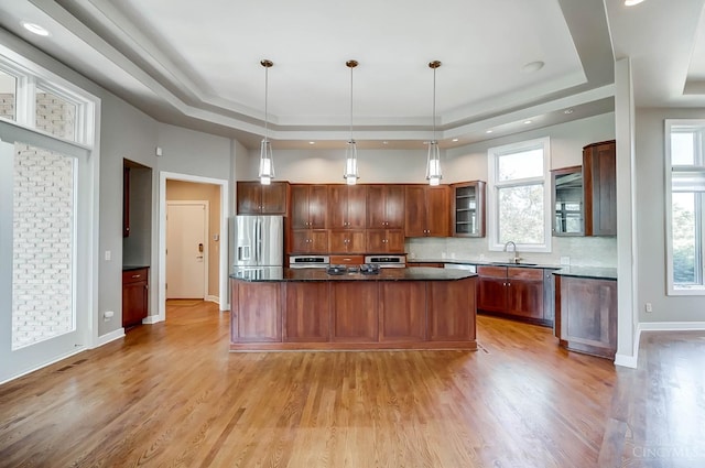4994 Maxwell Dr, Mason, OH 45040 - kitchen with stainless steel refrigerator with ice dispenser, a tray ceiling, decorative backsplash, light wood-style flooring, and a center island