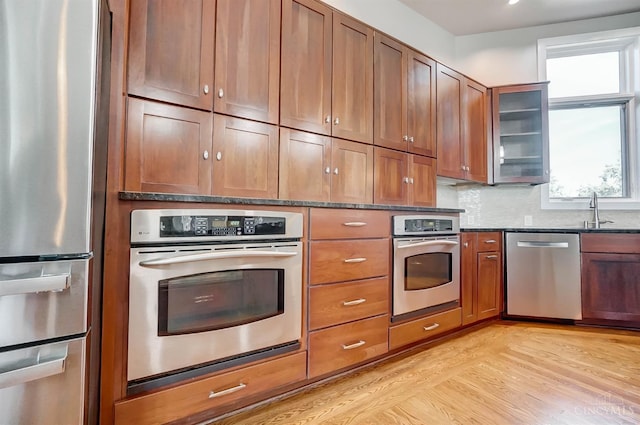 4994 Maxwell Dr, Mason, OH 45040 - kitchen with stainless steel appliances, dark stone countertops, light wood finished floors, glass insert cabinets, and brown cabinets