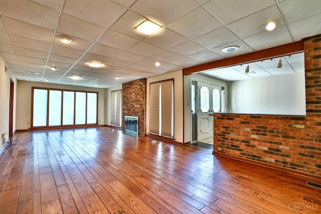 5868 Greenlawn Rd, Fairfield Twp, OH 45011 - unfurnished living room with brick wall, hardwood / wood-style flooring, a brick fireplace, and a paneled ceiling