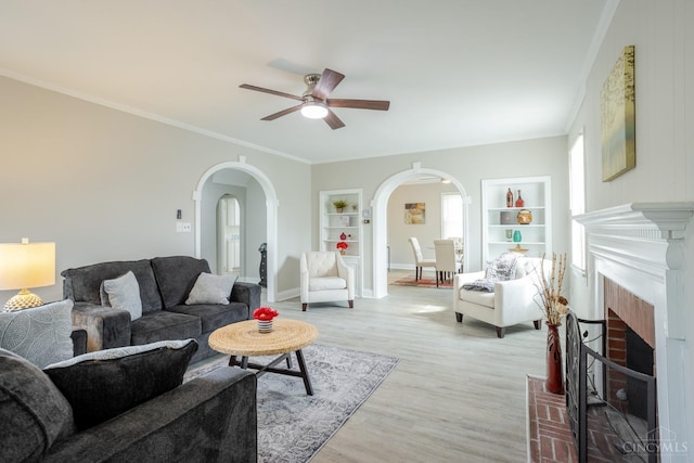 1744 Northampton Dr, Cincinnati, OH 45237 - living room with arched walkways, a ceiling fan, built in features, a fireplace, and light wood finished floors