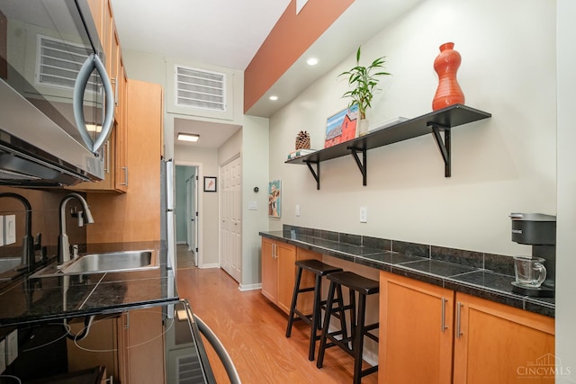 2100 Sinton Ave Unit 2, Cincinnati, OH 45206 - kitchen featuring stainless steel microwave, open shelves, light wood-style flooring, recessed lighting, and tile countertops
