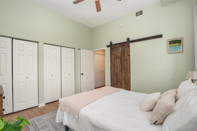 2100 Sinton Ave Unit 2, Cincinnati, OH 45206 - bedroom featuring a barn door, light wood-style flooring, two closets, and a ceiling fan