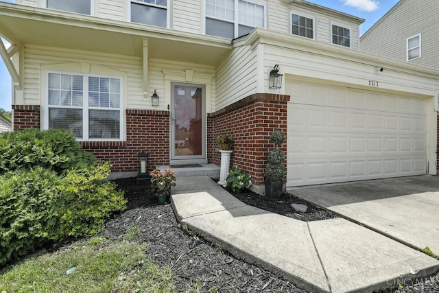 2317 Garrison Dr, Springfield Twp, OH 45231 - view of exterior entry with brick siding, a garage, and concrete driveway