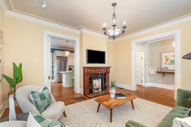 1117 Cypress St, Cincinnati, OH 45206 - living area with wood finished floors, a chandelier, a warm lit fireplace, and crown molding
