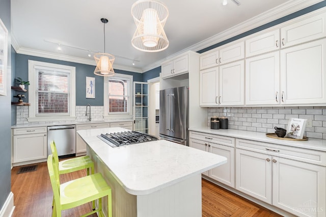 1117 Cypress St, Cincinnati, OH 45206 - kitchen featuring appliances with stainless steel finishes, decorative backsplash, white cabinetry, crown molding, and a center island