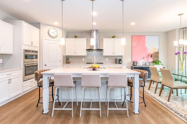 9302 W Meadow Dr, West Chester, OH 45069 - kitchen with wall chimney range hood, appliances with stainless steel finishes, light countertops, decorative backsplash, and white cabinetry