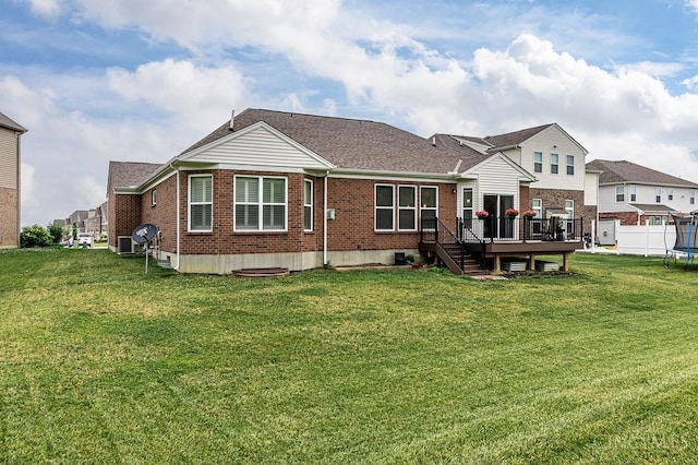 9302 W Meadow Dr, West Chester, OH 45069 - rear view of property featuring brick siding, a trampoline, a wooden deck, a yard, and a shingled roof