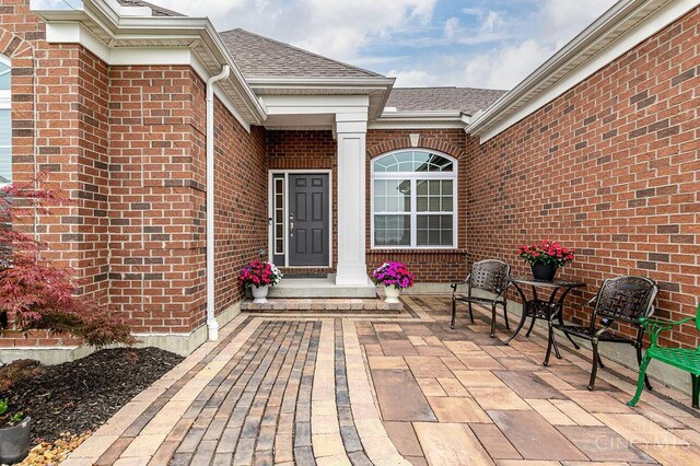 9302 W Meadow Dr, West Chester, OH 45069 - doorway to property featuring brick siding, roof with shingles, and a patio area