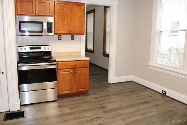 1841 Carll St, Cincinnati, OH 45225 - kitchen with stainless steel appliances, light wood finished floors, decorative backsplash, brown cabinets, and light countertops