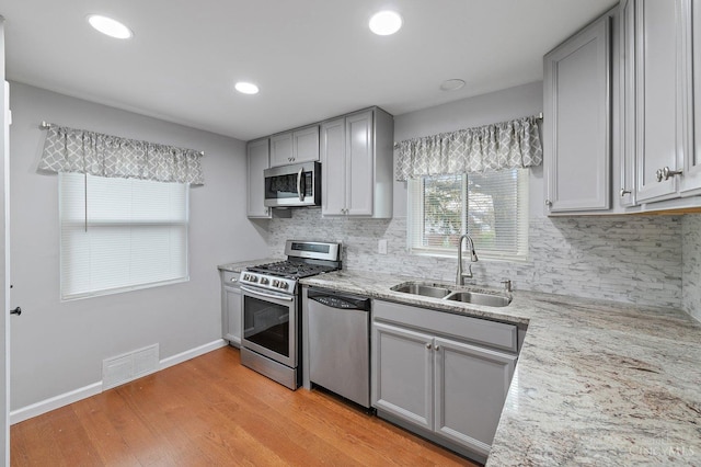 5611 Glengate Ln, Cincinnati, OH 45212 - kitchen featuring appliances with stainless steel finishes, gray cabinetry, tasteful backsplash, light wood-type flooring, and recessed lighting