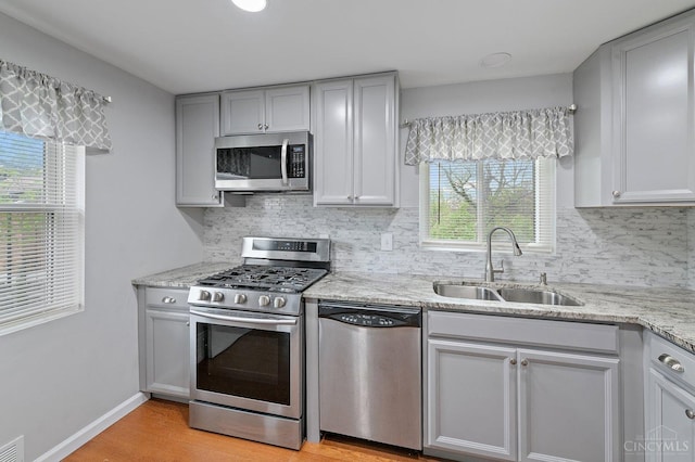 5611 Glengate Ln, Cincinnati, OH 45212 - kitchen with stainless steel appliances, decorative backsplash, light wood finished floors, and light stone counters