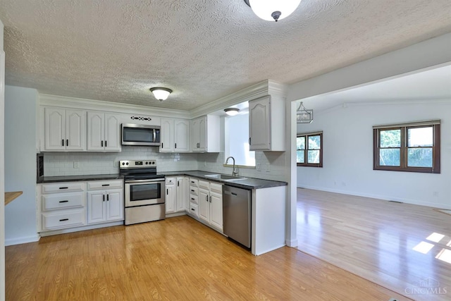 115 Treeline Ct, Harrison, OH 45030 - kitchen with appliances with stainless steel finishes, dark countertops, light wood finished floors, tasteful backsplash, and a textured ceiling