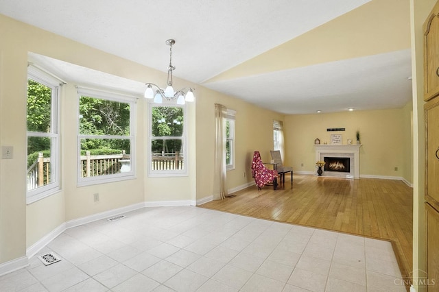 4653 Cardinal Dr, Union Twp, OH 45244 - unfurnished living room with vaulted ceiling, a warm lit fireplace, a chandelier, and light wood-type flooring