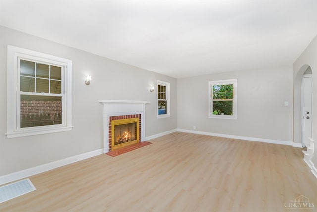 1427 Beaverton Ave, Cincinnati, OH 45237 - unfurnished living room featuring light wood finished floors, a brick fireplace, and arched walkways