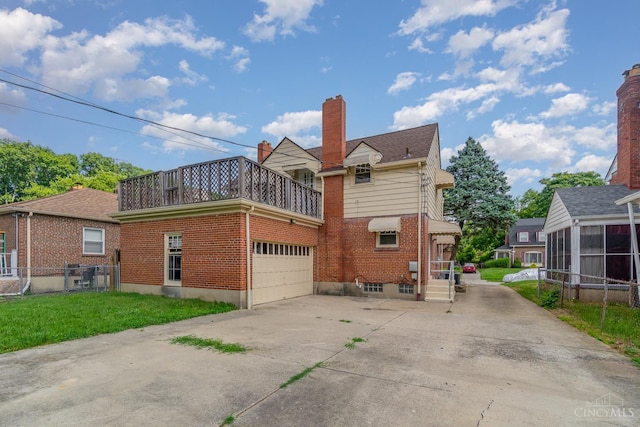 1427 Beaverton Ave, Cincinnati, OH 45237 - back of house with brick siding, concrete driveway, a chimney, an attached garage, and a balcony