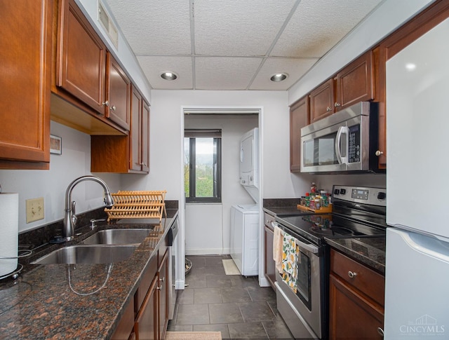 355 Grand Ave Unit 302, Cincinnati, OH 45205 - kitchen with appliances with stainless steel finishes, stacked washer / drying machine, dark stone counters, dark tile patterned floors, and a drop ceiling