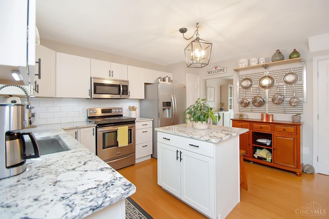 6711 Bayberry Ct, Hamilton Twp, OH 45039 - kitchen featuring stainless steel appliances, white cabinetry, decorative backsplash, hanging light fixtures, and light wood-type flooring