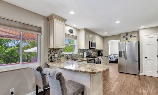 5817 Countryview Ter, Delhi Twp, OH 45233 - kitchen featuring stainless steel appliances, light stone countertops, cream cabinets, backsplash, and light wood-type flooring