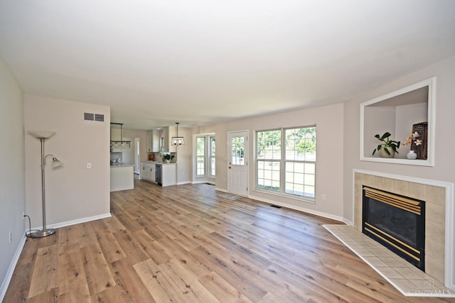 1055 Valley Wood Dr, Union Twp, OH 45103 - unfurnished living room with a tiled fireplace and light wood-style flooring