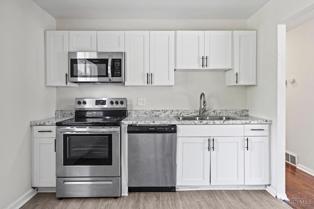 2016 Mistyhill Dr, Springfield Twp, OH 45240 - kitchen with stainless steel appliances, light wood finished floors, white cabinets, and light stone countertops