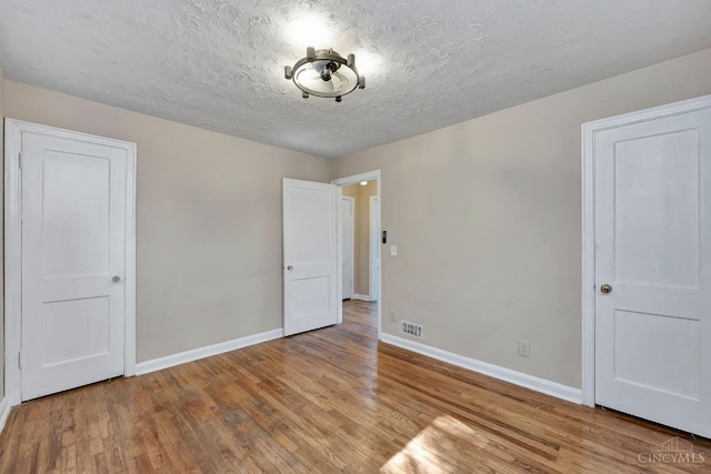 7866 Stillwell Rd, Cincinnati, OH 45237 - unfurnished bedroom with wood finished floors and a textured ceiling