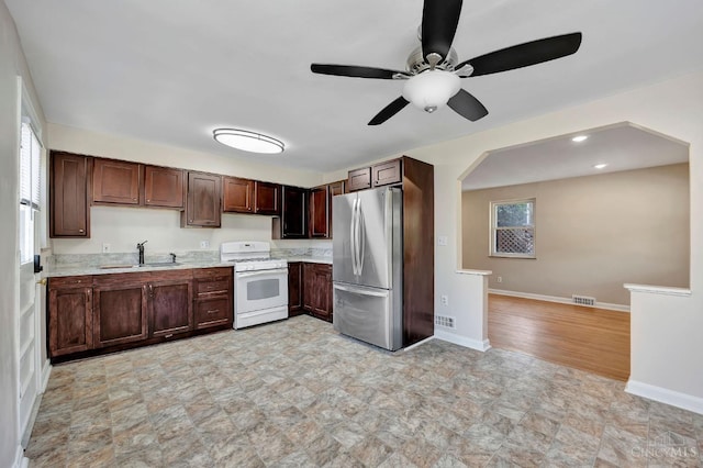 7866 Stillwell Rd, Cincinnati, OH 45237 - kitchen with white range with gas cooktop, freestanding refrigerator, ceiling fan, arched walkways, and plenty of natural light
