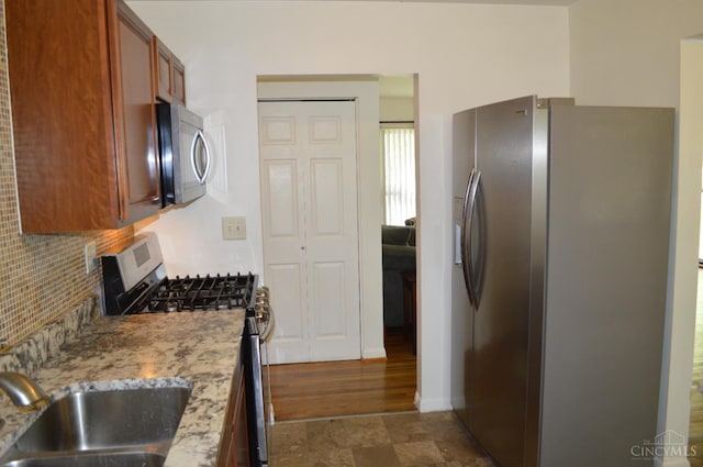 11528 Kenn Rd, Forest Park, OH 45240 - kitchen featuring stainless steel appliances, brown cabinetry, decorative backsplash, and light stone counters